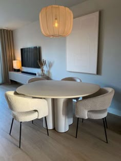 a dining room table with chairs and a television on the wall in the back ground