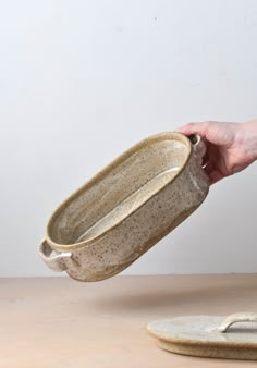 a person is holding a ceramic dish on a table