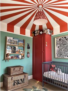 a baby's room decorated in red, white and blue with a striped ceiling