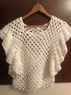 a white crocheted top hanging on a wooden hanger