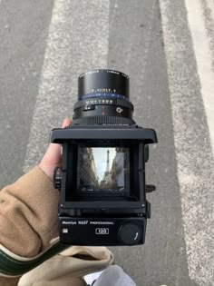 a person holding up a camera on the street