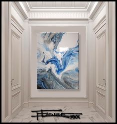 an abstract painting hangs in the middle of a room with white walls and flooring