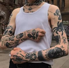 a man with many tattoos on his arms and hands is standing in front of an old building