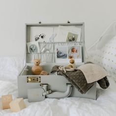 an open suitcase sitting on top of a bed next to pillows and toys in it