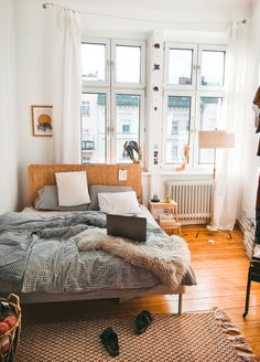 a bed room with a laptop on top of it next to a window and a rug