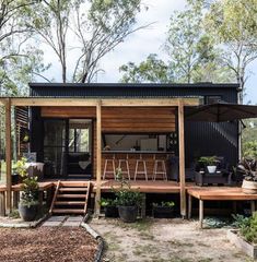 a small house made out of shipping containers in the middle of some trees and dirt