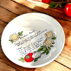 a white bowl with writing on it and tomatoes in the background next to some bread