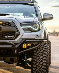 the front end of a gray truck with lights on