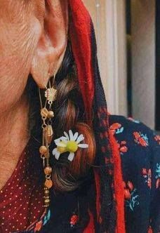 an older woman wearing earrings with flowers on them