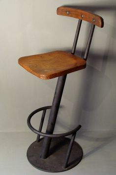 a wooden and metal stool against a white wall