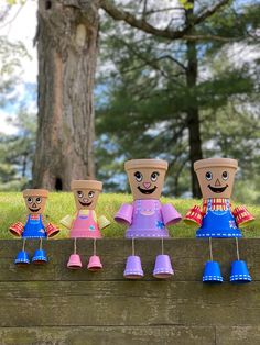 five paper dolls are lined up in front of a tree