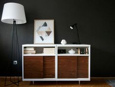 a white and brown bookcase with books on it in a living room next to a lamp