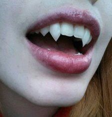 a close up of a woman's face with teeth and fangs on her lips