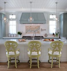 three green chairs sitting in front of a kitchen island