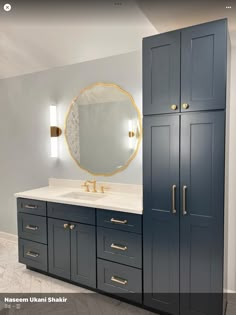 a bathroom with blue cabinets and a large mirror on the wall over the sink area