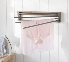 a pink shirt hanging on a clothes line next to an ironing board and dryer