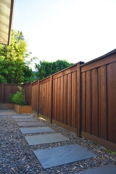 a wooden fence next to a gravel path