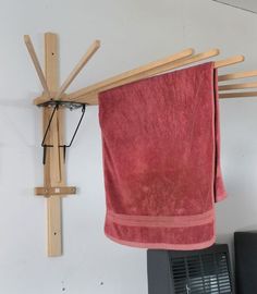 a red towel hanging on a clothes rack next to an air conditioner and fan