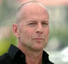 a bald headed man in a black shirt looking off to the side