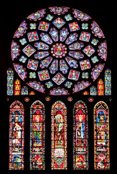 a large stained glass window in the middle of a dark room with many different colored windows