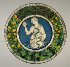 a decorative plate with an image of a man holding a snake and surrounded by leaves