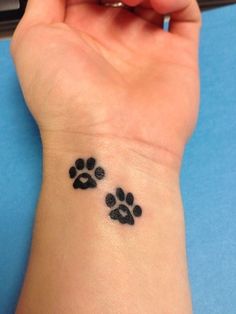 a person with a small tattoo on their wrist that has two paw prints on it