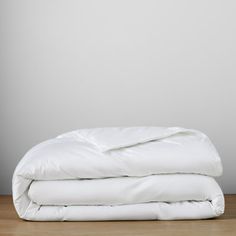 an unmade white comforter sitting on top of a wooden floor