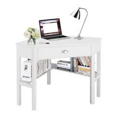 a laptop computer sitting on top of a white desk next to a book shelf and lamp