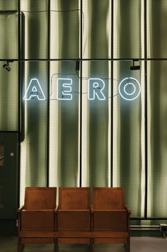 two chairs sitting in front of a neon sign that reads aero on the side of a building