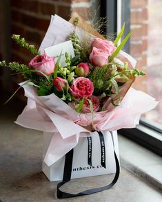 a bouquet of flowers sitting on top of a bag next to a window sill