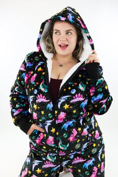 SAVE BIG on your electricity bills this winter and stay cosy and warm with a Space Dinosaur Sherpa Lined Onesie. The printed pattern features pop coloured dinosaurs in space helmets, stars and planets on a black background. Made from a new fluffy and toasty warm fabric that feels like you're wearing a cloud! So, zip yourself into a full, authentic, snuggly Onesie with no uncomfortable waistbands, no notches digging in and no drafty holes at the back! Range: FleeceStyle: Sherpa Lined OnesieSize R Dinosaur Onesie, Space Dinosaur, Warm Fabric, Fleece Leggings, Cozy Loungewear, Kangaroo Pouch, Sherpa Lined, Capri Leggings, In Space