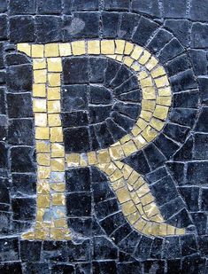 the letter p is made out of black and yellow tiles with gold letters on it