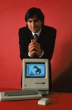 a man sitting in front of a computer with his hands folded over the keyboard and monitor