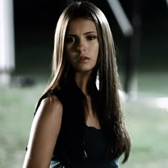 a woman with long hair standing in the dark