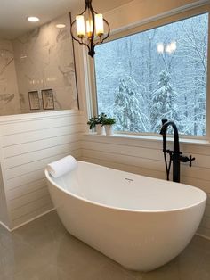 a large white bath tub sitting next to a window