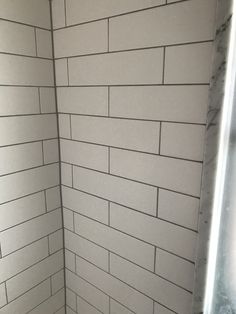 the corner of a shower stall in a bathroom with white subway tiles on the wall