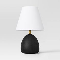 a black lamp with a white shade on it