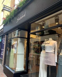 two mannequins are displayed in the window of a clothing store