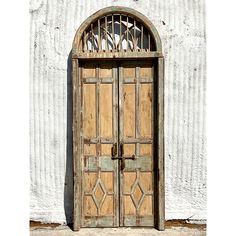 an old wooden door with iron bars on the top and bottom, in front of a white wall