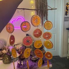 an assortment of citrus fruits hanging from a string in a kitchen with lights on the wall