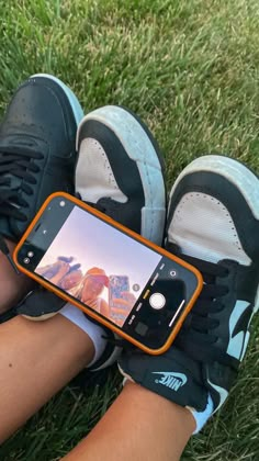 a person laying on the grass with their cell phone in front of them, taking a photo