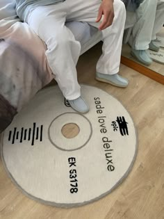 a man sitting on top of a bed next to a white rug with black writing