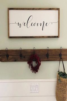 a welcome sign hangs on the wall above a basket and coat rack with a wreath