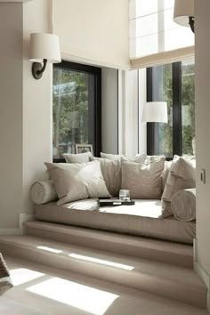 a living room filled with lots of white furniture and pillows on top of the couch