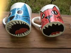 two coffee mugs decorated to look like animals with their mouths open and teeth painted on them