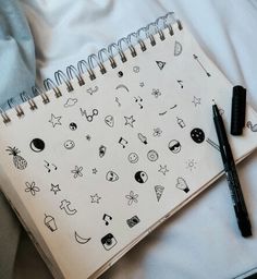 an open notebook with drawings on it next to a black pen and some white sheets