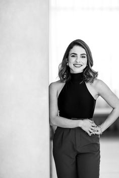 black and white photograph of a woman leaning against a wall with her hands on her hips