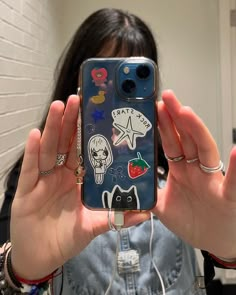 a woman holding up her cell phone with stickers on it