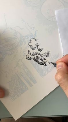 someone is drawing something with black ink on white paper