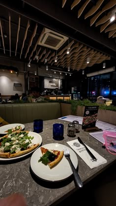 two plates with pizza on them sitting on a table